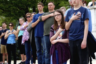 Group of people standing with hands on their hearts in a respectful and serious gesture, Washington