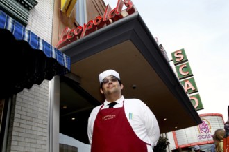Ice cream parlour worker in uniform poses smiling in front of Leopold's ice cream parlour with