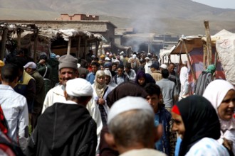 Bustling market in Msemrir with lots of people and stalls against a mountain backdrop, Msemrir,