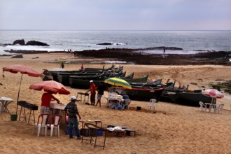 Fishing boats and food stalls in cloudy weather on Oulidia beach, Oulidia, Doukkala-Abda, Morocco
