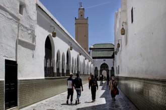Visitors walk along the arcades of the mausoleum in Moulay Idris under clear skies, Moulay Idris,