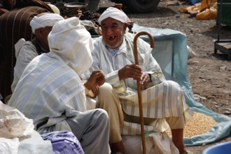 Men wearing traditional clothes talk at a market in Msemrir, Msemrir, Morocco