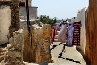 Narrow path between stone houses with colorful fabrics on clotheslines, Safi, Medina, Morocco