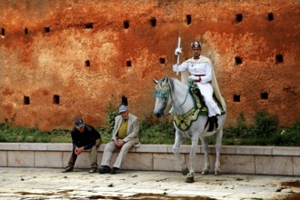 A guard in traditional uniform riding a horse next to people sitting, Rabat, Morocco