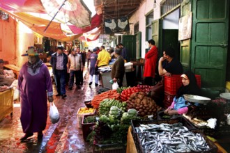 A lively market scene with a variety of fresh vegetables and people passing by, Tetouan, Medina,