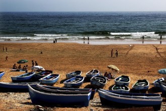 Blue fishing boats on beach with sea view and close people, Taghazout, Souss-Massa region, Morocco