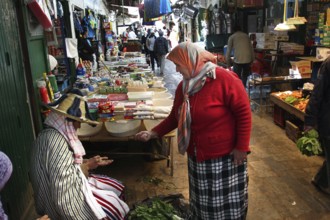 Two woman in traditional clothing talking at a busy market, Tetouan, Medina, Morocco