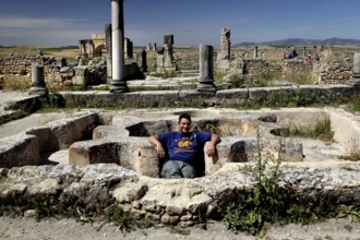 Visitors relax in the ruins of the Volubilis thermal baths, surrounded by ancient columns and stone