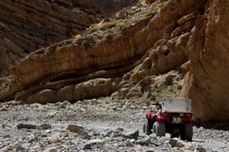 A quad bike surrounded by rocky cliffs in the gorge landscape, Tal, Tizgui n'Ouadda