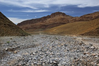 A dry, rocky landscape under a blue sky, valley, Tizgui n'Ouadda