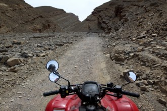 View from a motorcycle of a narrow, rocky path in a gorge, Tizgui n'Ouadda, Morocco