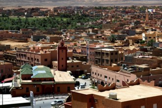 Townscape of Tinerhir with traditional buildings and green oasis behind them, Tinerhir, Morocco