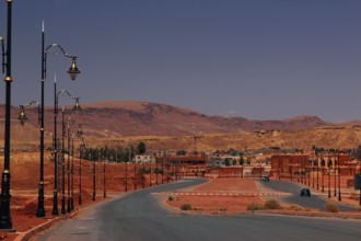 Curvy road with lanterns in sandy surroundings and hills in the background, Tinerhir, Morocco