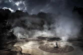 Steaming mud hole in dark, atmospheric surroundings in Wai-O-Tapu