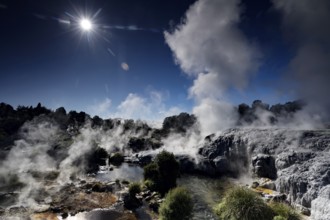 Sintered terraces with rising steam under the sun in the geothermal area of Te Puia, Rotorua, North