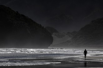 Person walking along the dramatic coastline of Bethells Beach, Te Henga, region, New Zealand