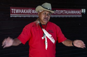 A Maori guide named Philipp explains Maori culture in a red and black outfit, Rotorua, Bay of