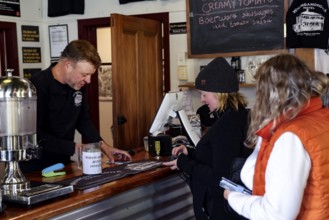 People at the Whangamomona Hotel communicating at reception in a cozy atmosphere, Whangamomona, New
