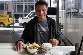 Man in a restaurant in Wellington enjoying a meal with an urban background, Wellington, North