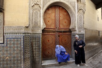 Two men in front of an artfully decorated wooden door with mosaic decoration, Fez, Fez el Bali,