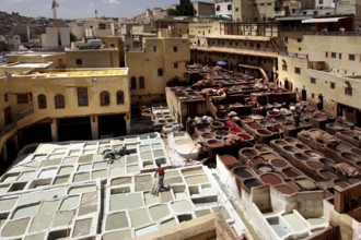 Traditional leather tannery in Fez with numerous paint basins and surrounding ancient architecture,
