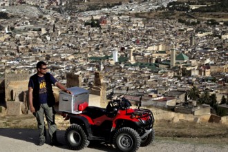 Man with quad bike in view of Fez from the Merinid Tombs, Fez, Fez el Bali, Morocco