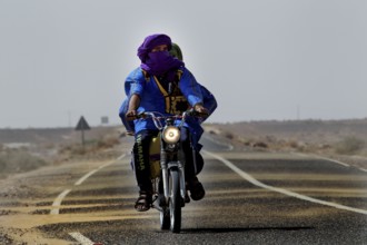 Motorcyclists on asphalt road in desert region near Merzouga, Merzouga, Morocco