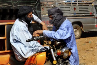 Two men in traditional clothing talking on a motorcycle, Guelmim, Guelmim-Oued Noun, Morocco