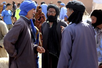 Three men in traditional clothing talking at a cattle market, Guelmim, Guelmim-Oued Noun, Morocco