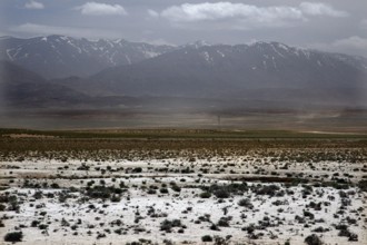 Wide barren landscape in front of the mountains of the High Atlas Mountains under a cloudy sky,