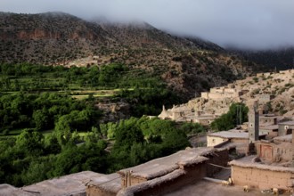 View of a traditional village in the valley surrounded by green hills of the High Atlas Mountains,