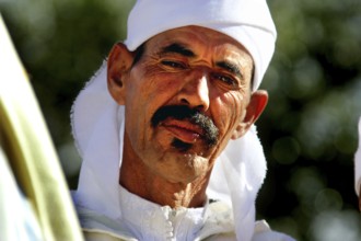 Man in traditional dress at the Rose Festival in El Kelâa m'Gouna, serious expression, El Kelâa