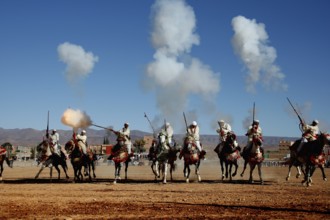 Group of riders fire guns and creates clouds of smoke during a traditional Fantasia ritual, El