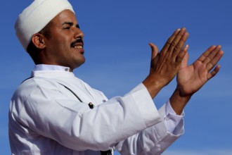 Man in traditional dress claps rhythmically at Berber Festival, Ma El Kelâa M'gouna, Fête des