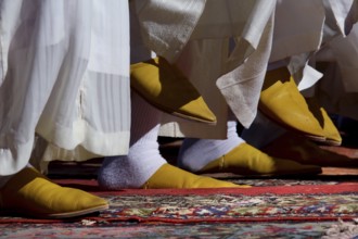Close-up of traditional yellow Berber footwear on an ornate carpet, El Kelâa m'Gouna