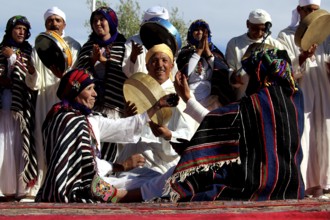 Gathering of men and woman wearing colorful Berber clothes holding drums, El Kelâa m'Gouna
