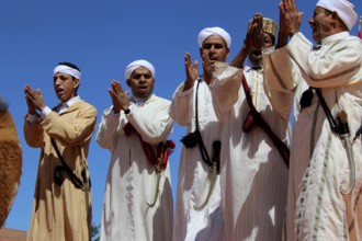 Group of men clapping to the beat, dressed in traditional Berber garments, El Kelâa m'Gouna