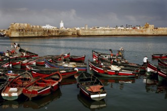 View of a medieval fortress from the harbor with lots of red and black boats, El Jadida, harbor,