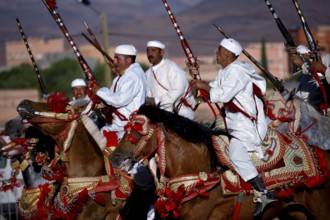 Fascinating parade of riders in white dress with magnificently decorated horses at a Fantasia, El