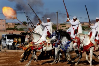 Riding group shoots in sync with rifles and creates fire and smoke in the midst of a traditional