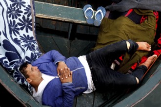 A man sleeps relaxing on blankets in a boat in the harbor, El Jadida, harbor, Morocco