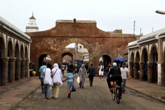 People walk through a historic stone gate in the souk of Essaouira, Essaouira, Morocco