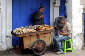 Vendor offers bread from a handcart in Essaouira souk, Essaouira, Morocco