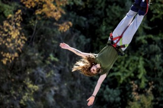 Headlong jumper bungee jumping amidst colorful autumn leaves, Queenstown, Otago, New Zealand