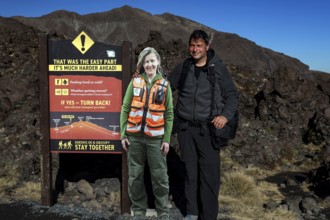 Rangers and hikers next to a warning sign at Tongariro Alpine Crossing, Tongariro National Park,