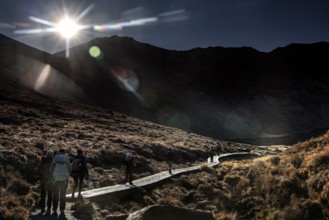 Hikers on the Tongariro Alpine Crossing with bright sunlight in the mountains, Tongariro National