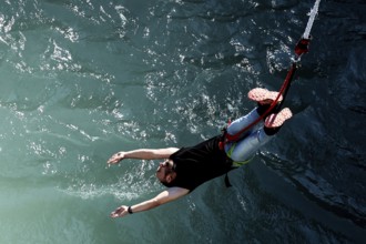 Person bungee jumping with arms extended over water, Queenstown, Kawarau Bridge, New Zealand