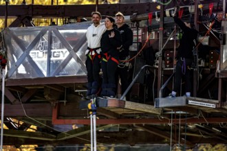 Two people are ready for a bungee jump from the Kawarau Bridge, the excitement is palpable,