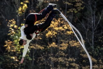 Partner bungee jump in spectacular acrobatics against a backdrop of autumn leaves, Queenstown,