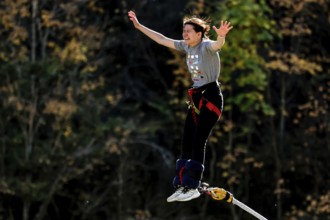 Female bungee jumping off Kawarau Bridge in the midst of autumn forest scenery, Queenstown, Otago,